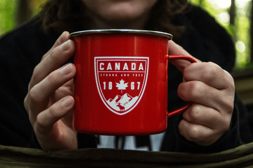 Close up of a person holding a mug with Canada and 1887 on the mug, showing the year Canada was founded. 
